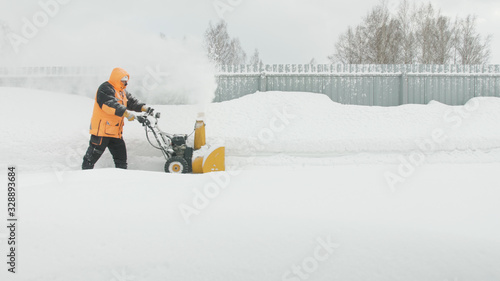 Man cleans snow with a snow thrower goes left to right