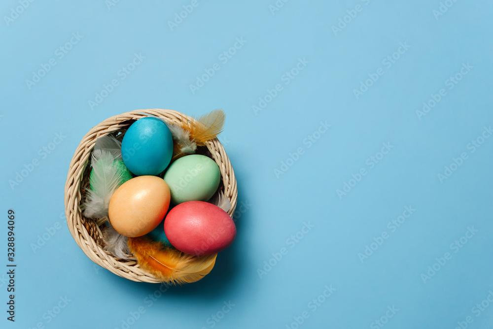 colorful Easter eggs in a basket among feathers colorful Easter eggs in a basket among feathers