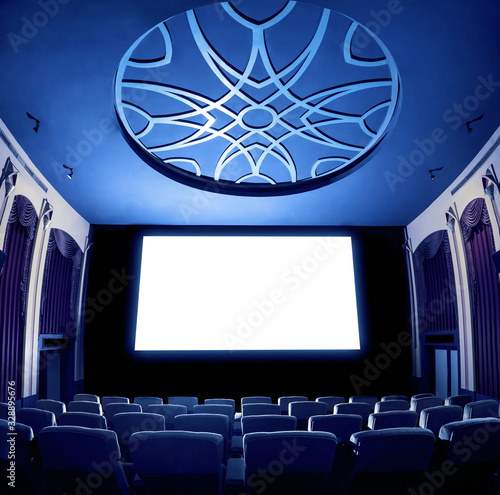 Cinema theater screen in front of seat rows in movie theater showing white screen projected from cinematograph. The cinema theater is decorated in classical style for luxury feeling of movie watching. photo