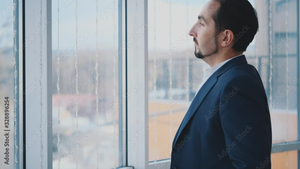 Businessman in formal suite stands in front of panoramic window with city view. Serious man. Profile view. Man crosses his arms. Close up. Animation. 4K. Businessman in formal suite stands in front of panoramic window with city view. Serious man. Profile view. Man crosses his arms. Close up. Animation. 4K.
