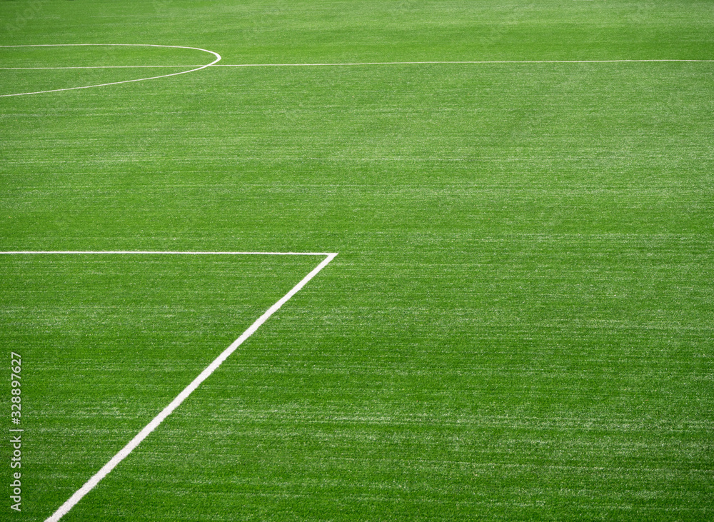 Green football field with fresh green grass and white lines. Abstract background