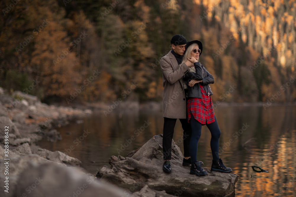A man hugs a woman near a lake. Couple of lovers stand together near a mountain lake