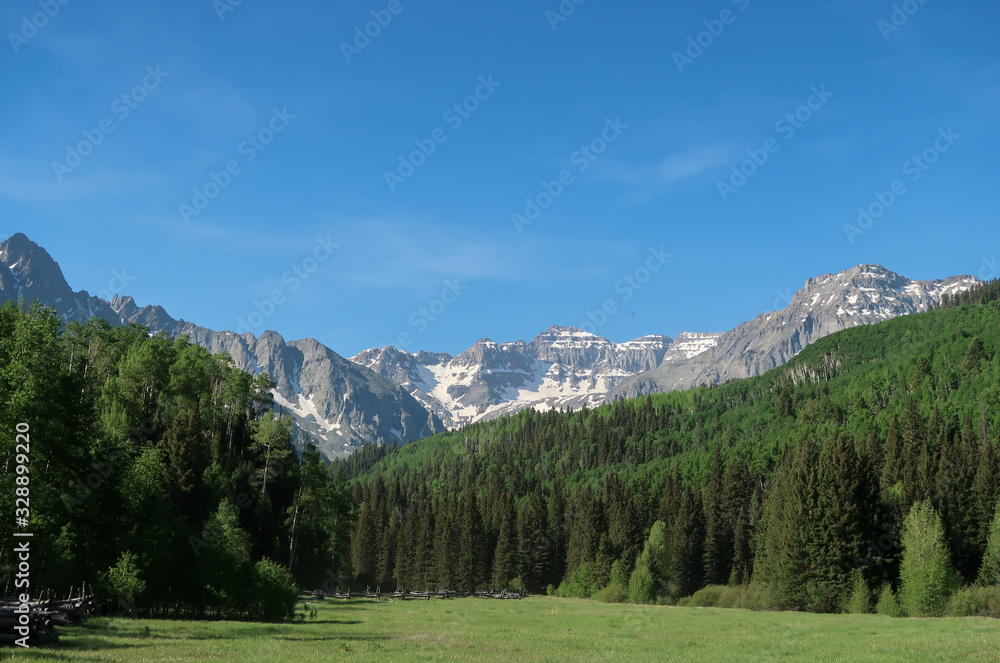 Landscape of meadow, forest and snow-dappled mountains in Colorado
