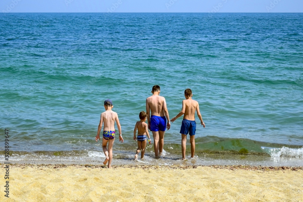 Group of boys on sea coast. Guys go swimming in sea.