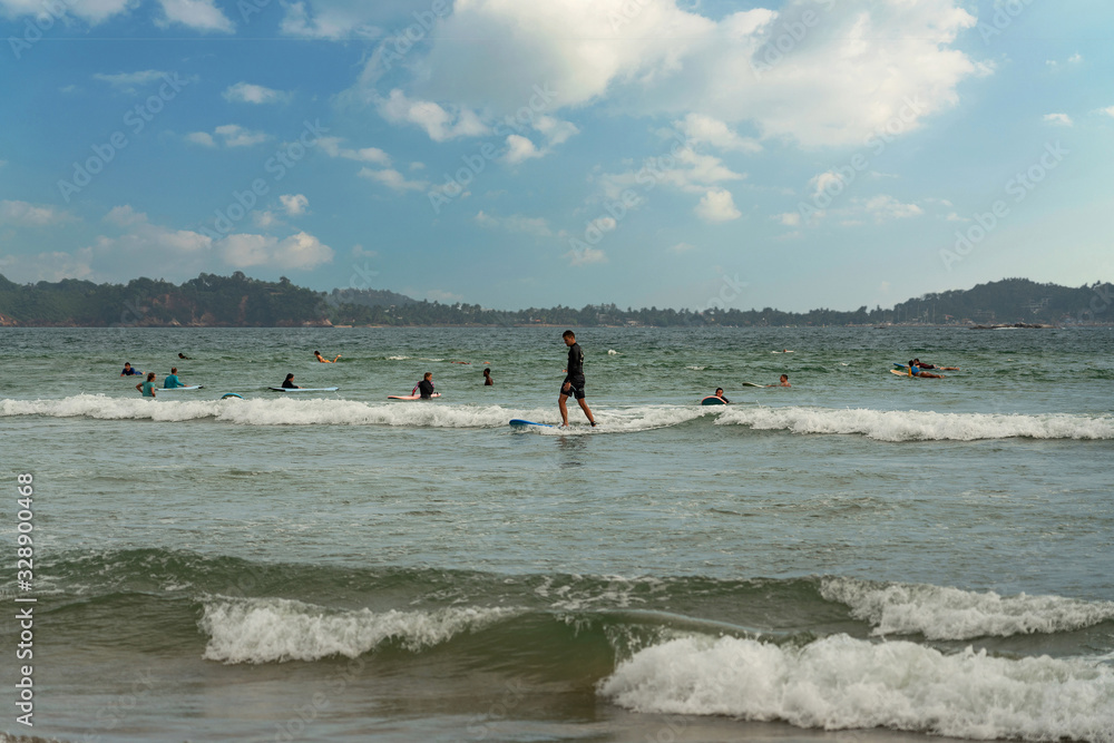 Surfers on the boards in ocean waves, Sri Lanka resort.