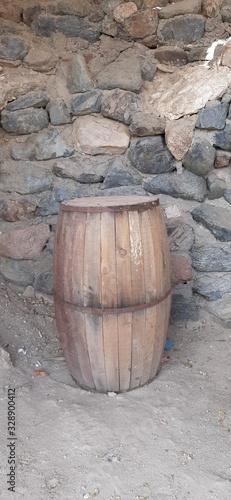 Wooden brown barrel against a stone wall.