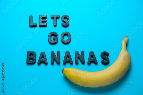 inscription lets go bananas and fresh yellow banana on a blue background