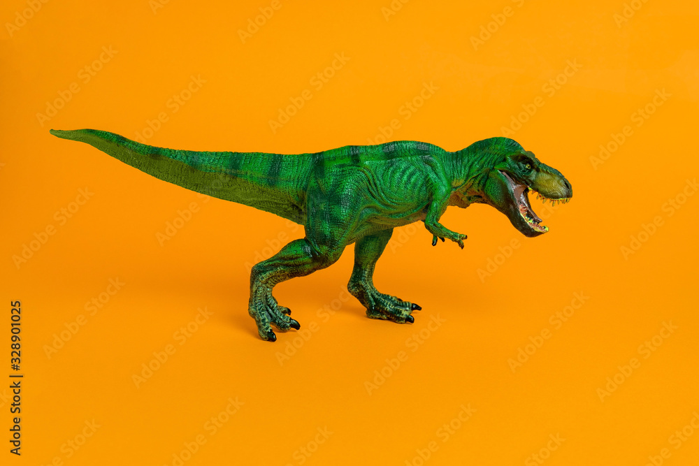 Obraz premium zielona zabawka dinozaura z otwartymi ustami na żywym pomarańczowym tle