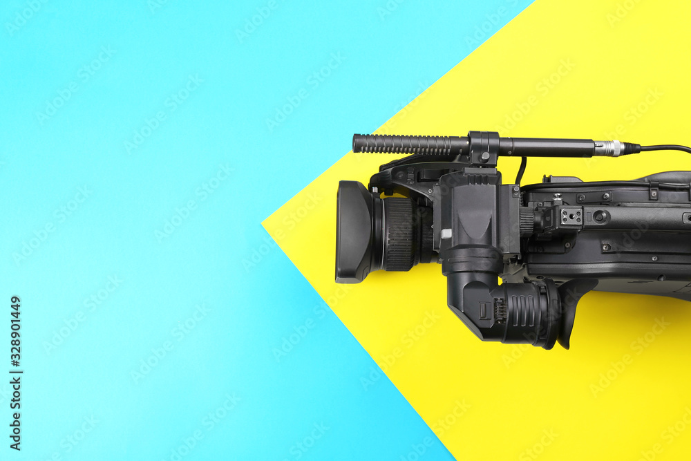 Modern video camera on color background, top view. Space for text