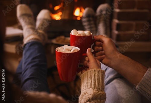 Φωτογραφία Lovely couple with sweet cocoa near fireplace indoors, closeup