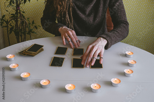young woman lays out black cards on the table with candle lights