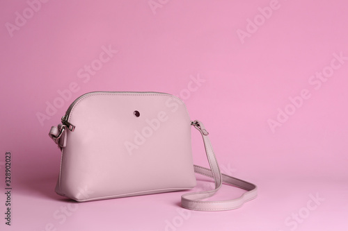 Stylish woman's bag on light pink background. Space for text