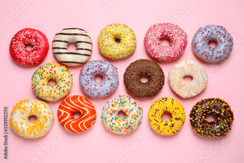 Delicious glazed donuts on pink background, flat lay