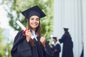 A young female graduate against the background of university graduates.