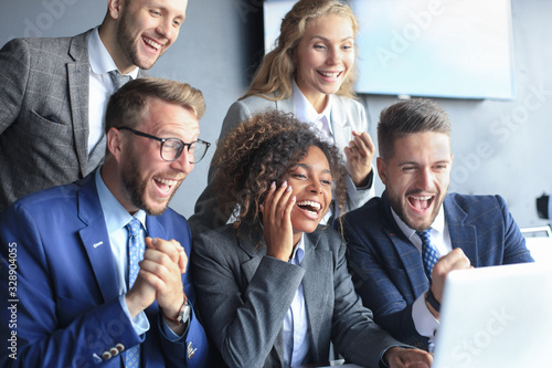Happy business people laugh near laptop in the office. Successful team coworkers joke and have fun together at work.