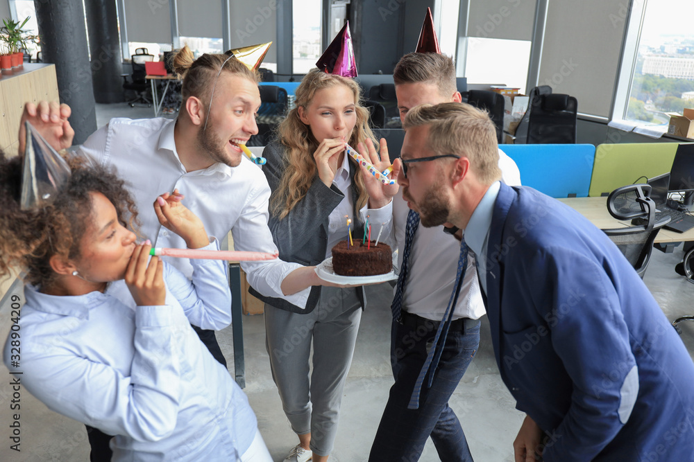 Happy business team with birthday cake are greeting colleague at office party