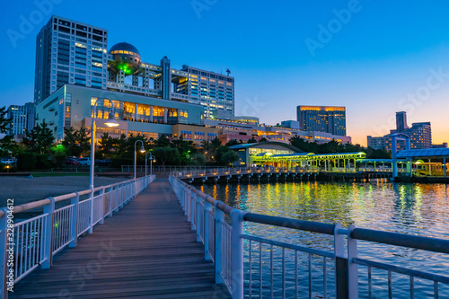 Japan. Odaiba Island Embankment. Unusual building in Tokyo. Modern architecture of Japan. Dawn on the island of Odaiba. Embankment of morning Tokyo. Wooden marina leads to the city promenade photo