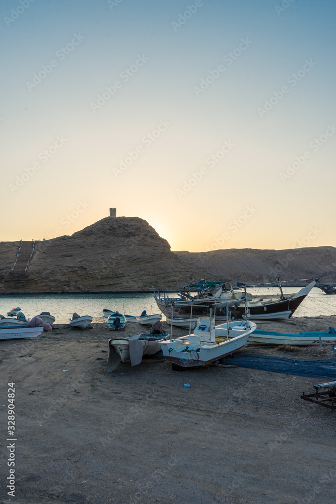Boats stranded with Al Ayjah castle in the background at Sur's bay, Oman