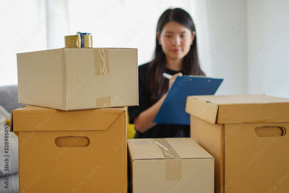Asian woman checking and packing the carton box prepare to move to new house or check package before send to customer from shopping online by checklist with blur motion, packing and checklist concept Asian woman checking and packing the carton box prepare to move to new house or check package before send to customer from shopping online by checklist with blur motion, packing and checklist concept