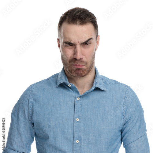 Disgusted casual man frowning while wearing blue shirt