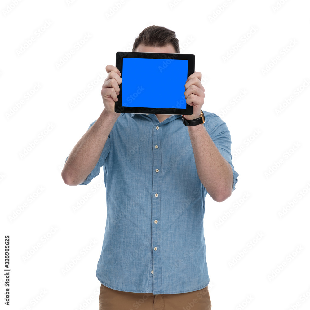 Young casual man covering his face with empty tablet Young casual man covering his face with empty tablet