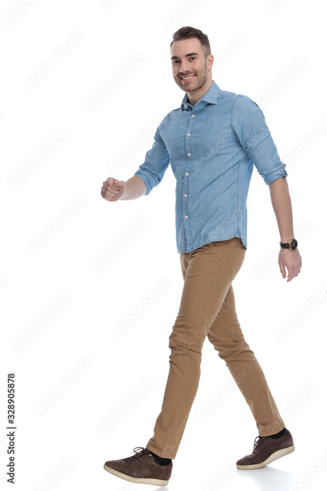 Fototapeta premium Side view of handsome casual man smiling and stepping