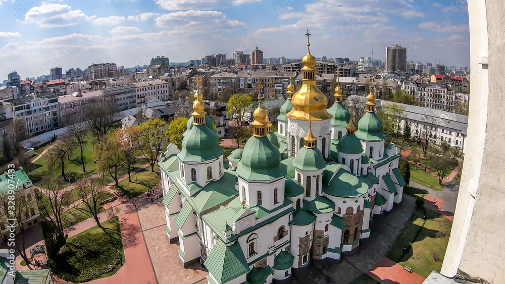 St Sophia's Cathedral in Kiev, Ukraine seen from the bell tower. The cathedral is white with green rooftops and golden turrets. Complex building, consisting of many smaller rooftops and towers.
