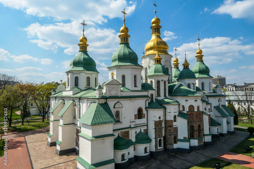 St Sophia's Cathedral in Kiev, Ukraine seen from the bell tower. The cathedral is white with green rooftops and golden turrets. Complex building, consisting of many smaller rooftops and towers.