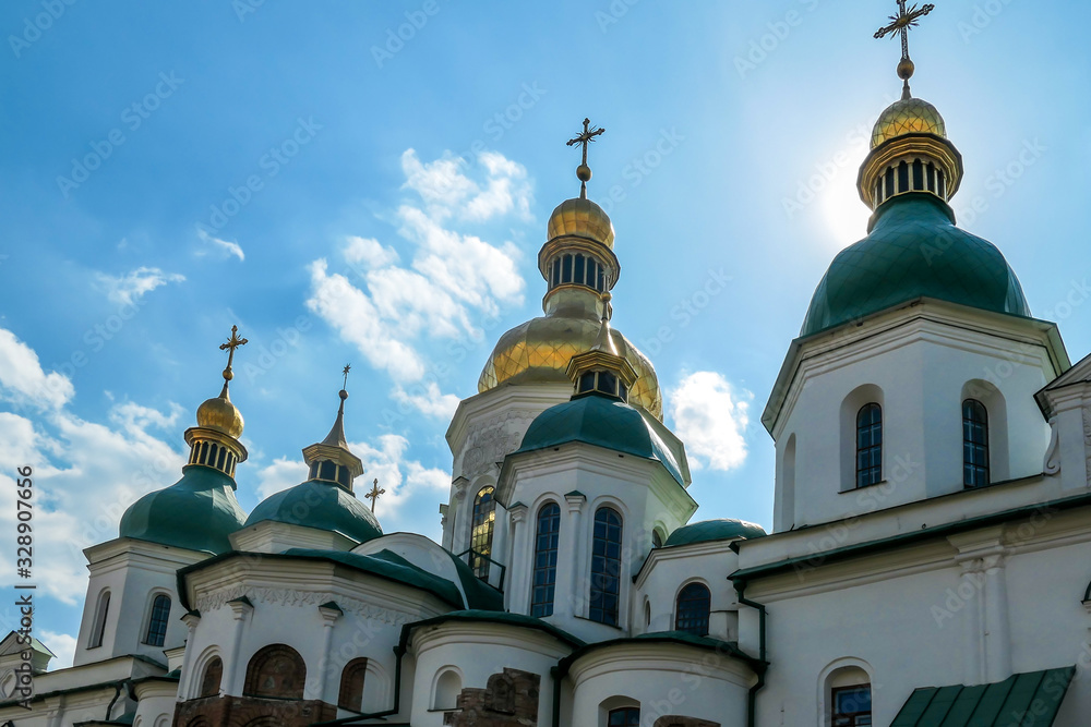 Close-up on the rooftops of St Sophia's Cathedral in Kiev, Ukraine. The cathedral is white with green rooftops and golden turrets. Complex building, consisting of many smaller rooftops and towers.