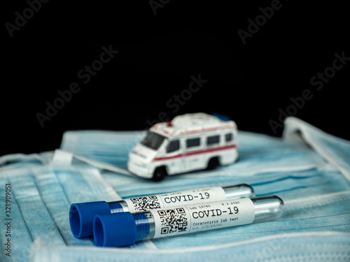 Test tube sample COVID-19 test on background from face masks, ambulance car in the background