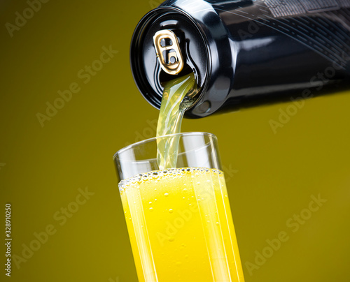 Carbonated energy drink pouring from an aluminum can into a glass