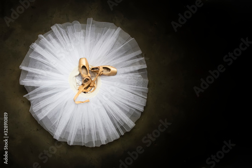 Ballet shoes with ribbons on a white tutu in a dance studio photo