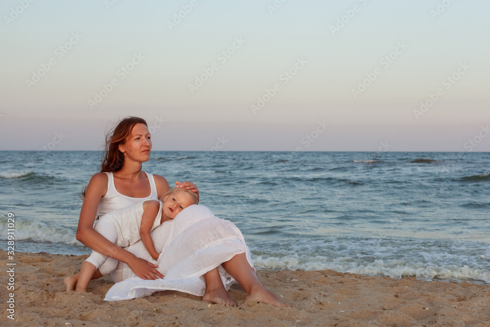 Portrait of a beautiful young mother and daughter on the seashore. Portrait of a beautiful young mother and daughter on the seashore.