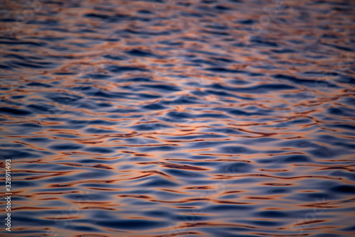 Close-up of gentle sea waves in the golden sunlight. Light reflections on the water.