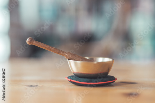 Baby singing bowl on a rustic wooden table. Instrument for meditation and message.