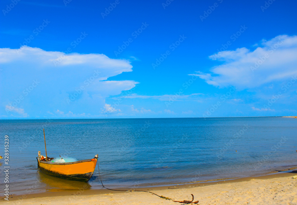 A fishing boat docked at the beach with beautiful blue sea and sky