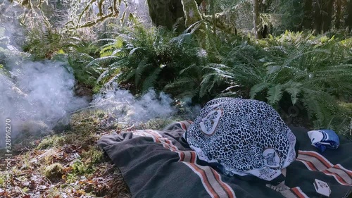 Woman shaman holding a burning bowl of plant medicine and bending over in prayer to her ancestors photo