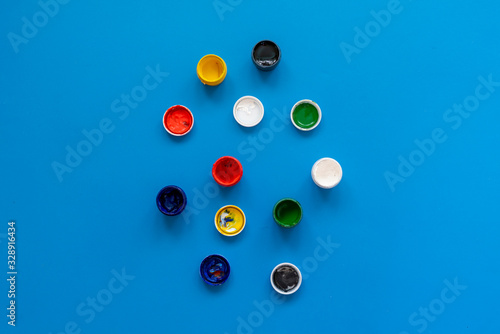view from above of the colorful paints gouache in pots or cans on the colorful background