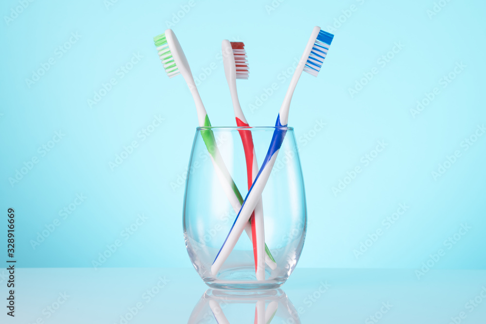 Colored toothbrushes in a glass. Bathroom wall. Light blue background. Copy space. Colored toothbrushes in a glass. Bathroom wall. Light blue background. Copy space.