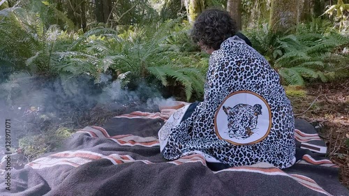 Woman shaman raising up to kneeling holding a burning bowl, praying to her ancestors
