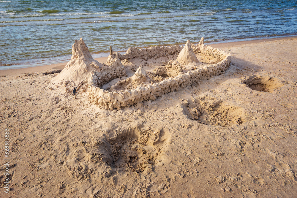 Sand castle on beach on sunset. A sandcastle on a sandy coast, blue sky. House with high towers on sandy shore. Sand castle on beach on sunset. A sandcastle on a sandy coast, blue sky. House with high towers on sandy shore.