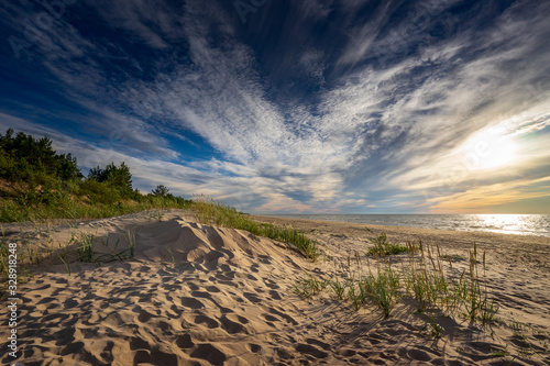 Sand dunes on the beach. Sunny coast, grass and blue sky. Sunset light in northern Latvia, Europe.
