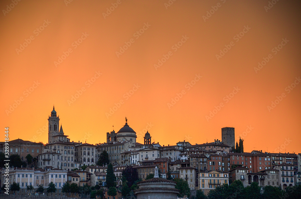 Colorful sunset in Bergamo, famous tourist destination in Lombardy, Italy. View to upper town with dramatic sky.