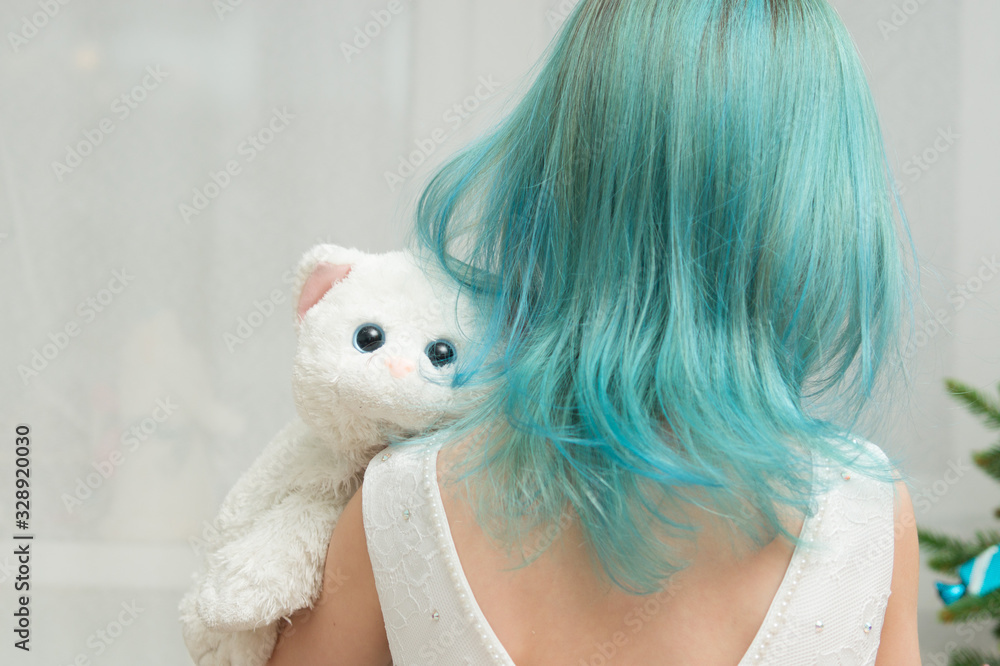 girl with blue hair in a white dress and a toy cat on the background of the New Year tree girl with blue hair in a white dress and a toy cat on the background of the New Year tree