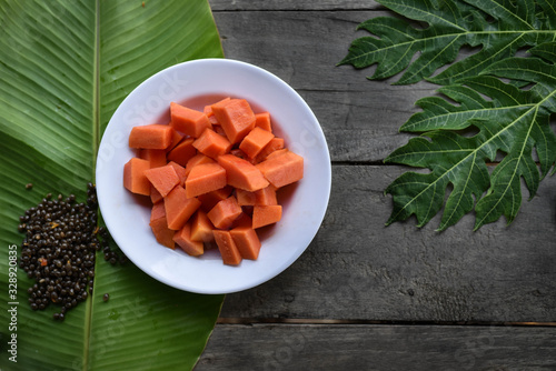 Papaya slices in a dish on wooden background.