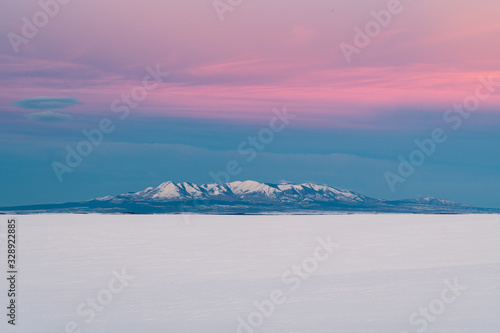 A Beautiful Winter Landscape of Sunrise with Open Field and Mountains in Background 