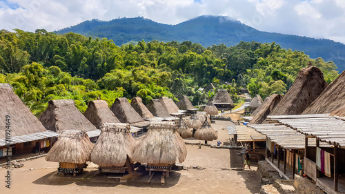 Inside view on the traditional Bena village in Bajawa, Flores, Indonesia. There are many small houses around, made of natural parts like wood and straw. History and tradition. Big volcano in the back photo