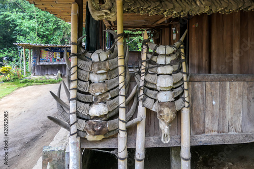 Cow horns hanging on wooden stilts on the side of a house in the traditional Bena village in Bajawa, Flores, Indonesia. Spiritualism and totems. History and tradition mingling with presence. photo
