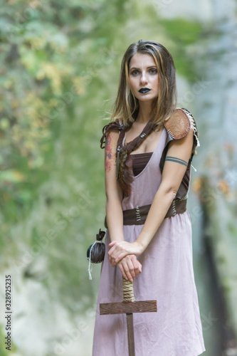 Beautiful blonde viking woman with a shield and a sword near a waterfall, Pruncea Casoca, Romania photo