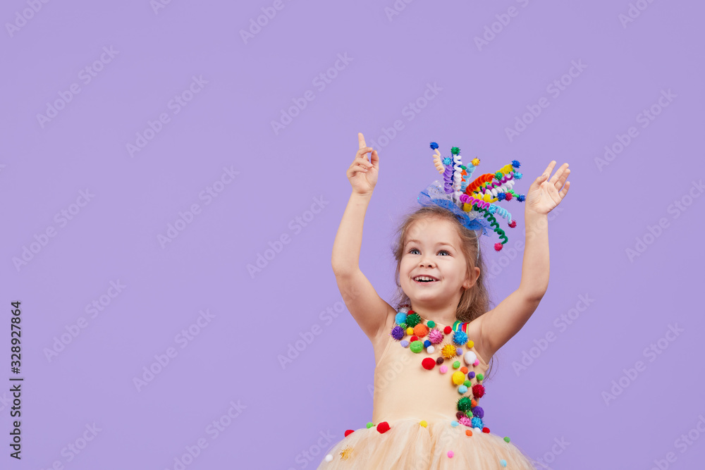 Childrens birthday party, masquerade. Little happy toddler child girl in a puffy tutu fancy dress, having fun on Violet background. Space for text